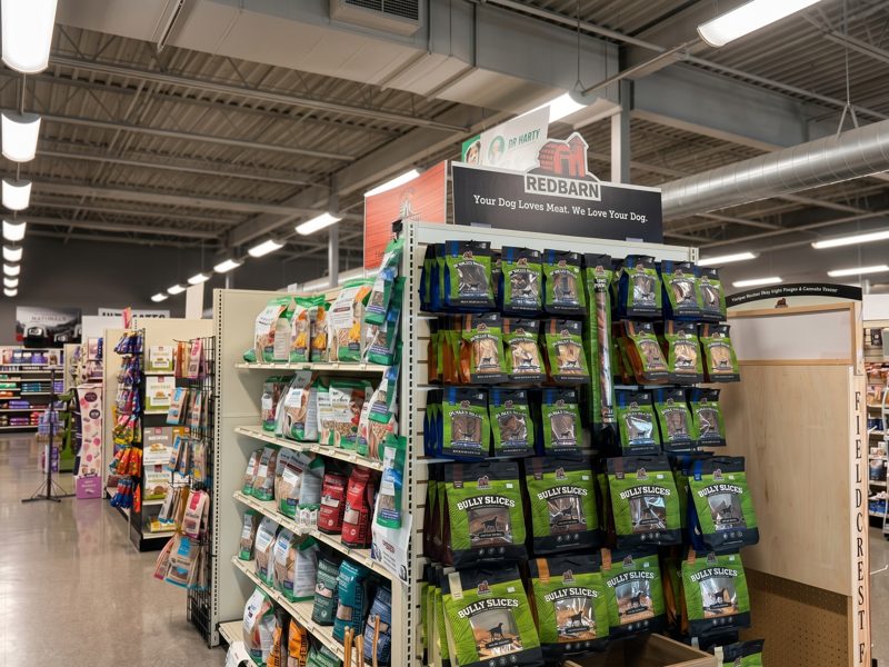 An endcap of bagged treats and chews down a bright aisle